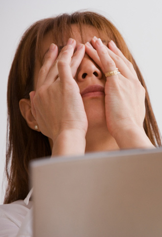 Woman at laptop, rubbing eyes